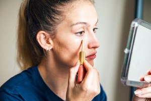 Woman Applying Make-up under her Eyes