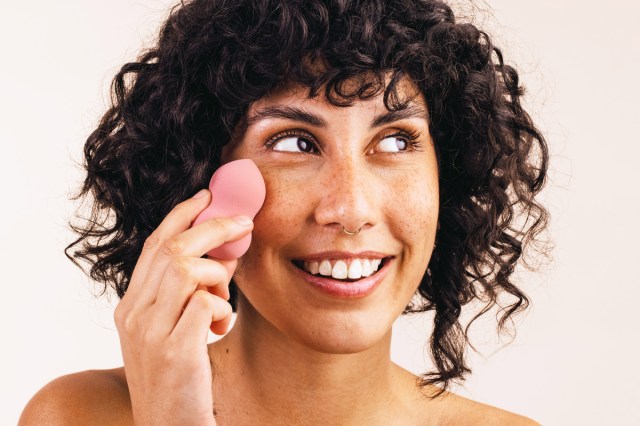 woman using a beauty blender on her face