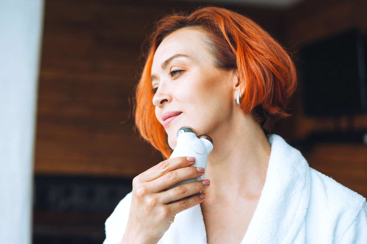 Woman using microcurrent device on her face